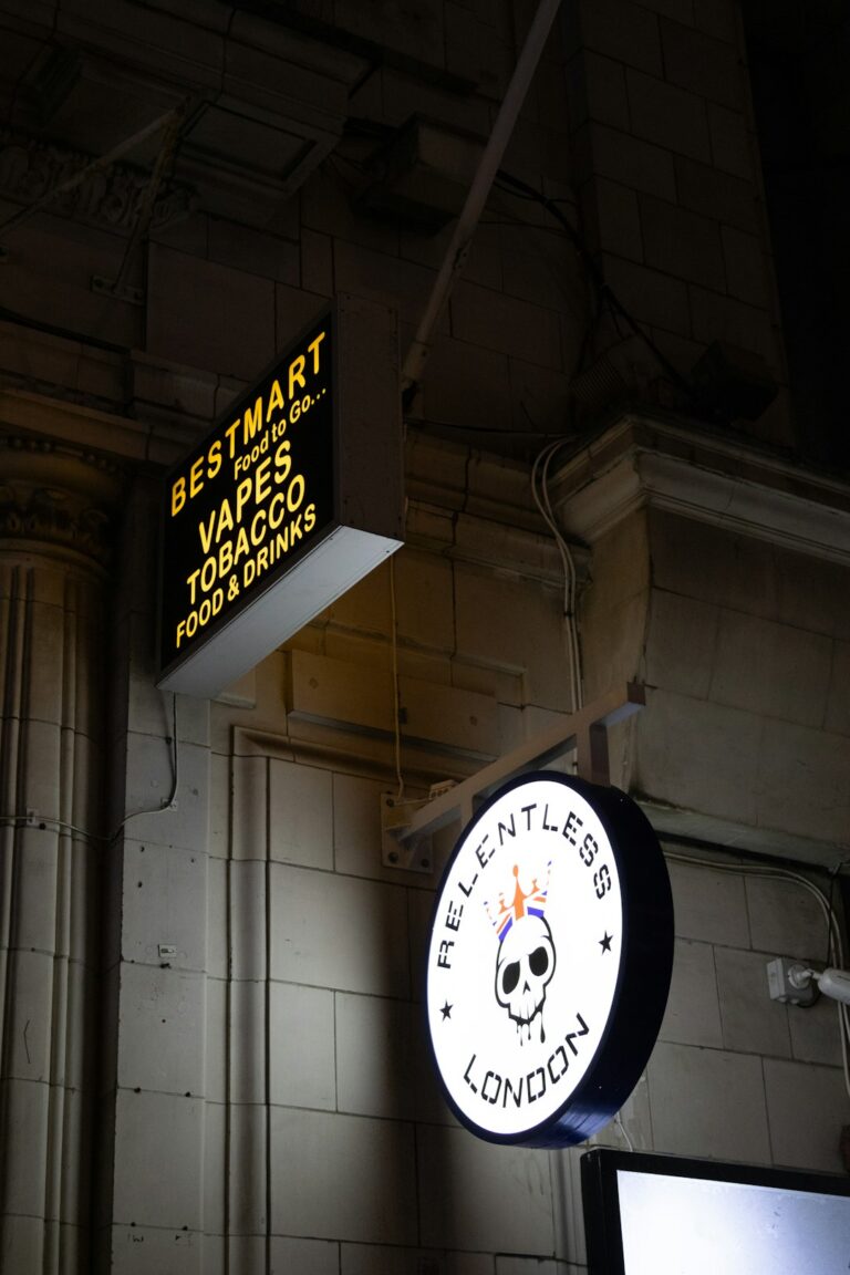 A small business owner using a tablet to update a menu on a brightly lit digital sign inside a café.