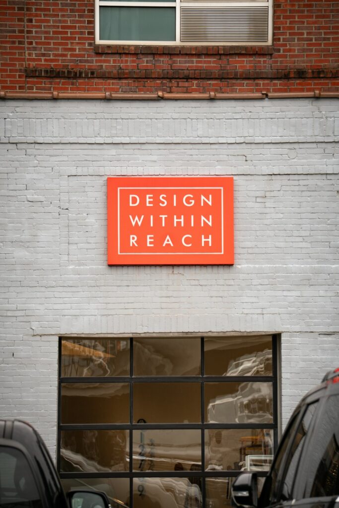 A person measuring a large outdoor sign with tools and materials arranged on the ground nearby.