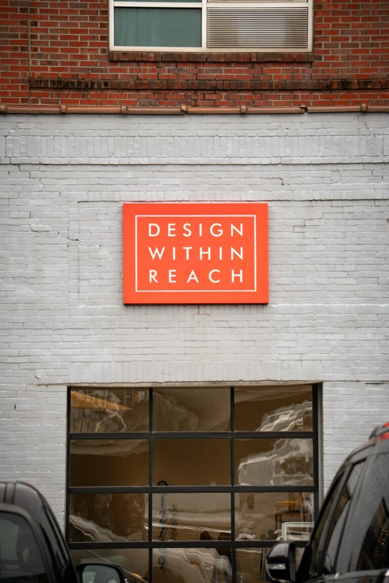 A person measuring a large outdoor sign with tools and materials arranged on the ground nearby.