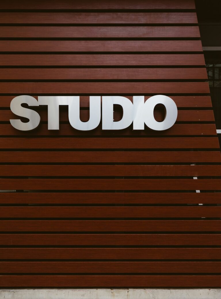 A storefront with clear illuminated lettering, window graphics, and pedestrians approaching the entrance.