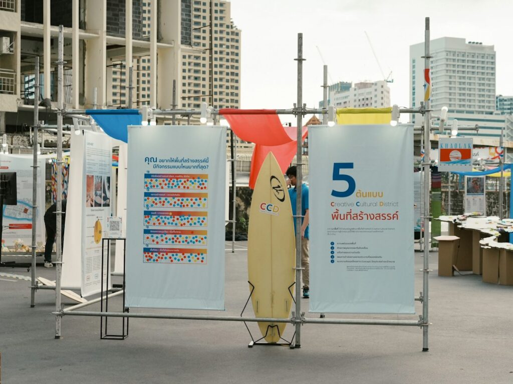 A staff member assembles a retractable banner beside a registration table in a bright indoor event space.